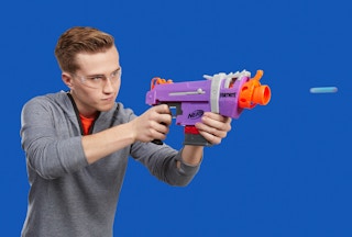stock photo of teen boy playing with nerf fortnite smg-e blaster on blue background