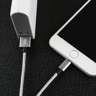 An iPhone plugged in to a charging cord.