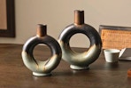 Lifestyle image of 2 circle hallow ceramic vases (2-tone) in home setting on a table