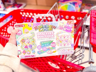 hand holding a rainbow loom bracelet boutique over a target cart