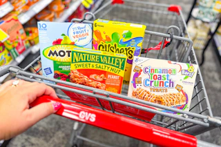 person pushing a cart with motts, gushers, nature valley bars, and cinnamon toast crunch cereal bars