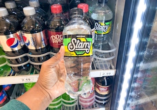 Someone taking a Starry lemon lime soda from a drink fridge at Publix