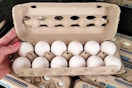 hand touching an open carton of kroger eggs