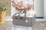 woman carrying diaper caddy and baby