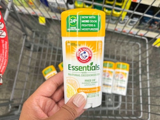 hand holding one Arm and Hammer deodorant in front of shopping cart with more