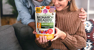 a person holding a bag of flower seed mix 