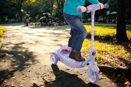 child riding a Huffy Disney bubble scooter in the park