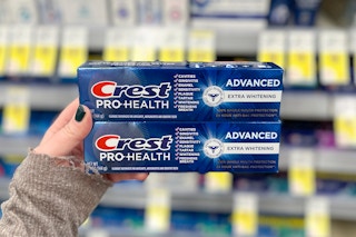 hand holding two tubes of crest toothpaste