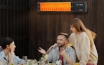 an outdoor patio heater on a fence where people are sitting