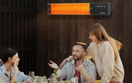 an outdoor patio heater on a fence where people are sitting