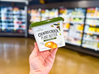 hand holding a tub of country crock plant butter