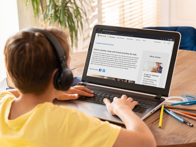 A kid using a laptop looking at Microsoft summer camp webpage