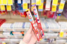 person holding 2 cvs health toothbrushes