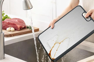 a woman washing a titanium cutting board