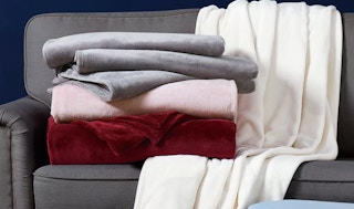 a stack of velvet throws on a grey couch
