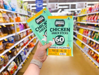 hand holding two packs of mighty spark snack sticks in walmart aisle