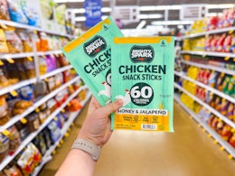 hand holding two packs of mighty spark snack sticks in walmart aisle