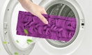 a hand putting a purple mop pad in a washing machine