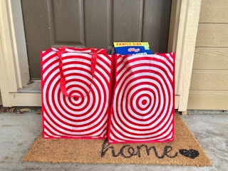 Two Target reusable grocery bags on a welcome mat on front doorstep.