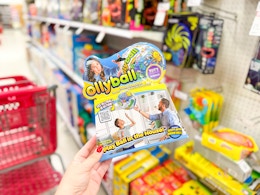 hand holding an ollyball in front of a target shelf