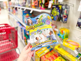 hand holding an ollyball in front of a target shelf