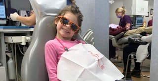 young happy child wearing sunglasses and a bib at the dentist