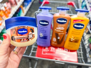 hand holding Vaseline bottle in front of Vaseline lotions inside shopping cart