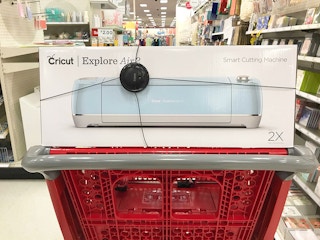 A Cricut Explore Air 2 sitting on top of a Target shopping cart in the crafting supplies aisle at Target.