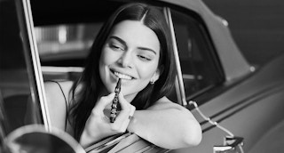 Kendall Jenner in a car using a teeth whitening pen.