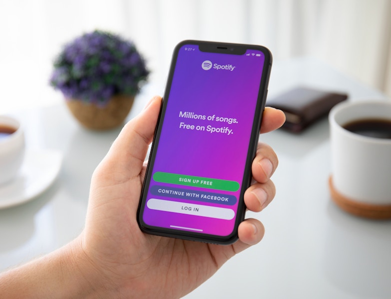 A man holding his phone and looking at the Spotify sign up page for the free plan