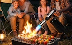 a person using a torch on a grill outside 