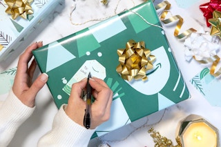 A person writing a name onto a wrapped present with Amazon gift wrap