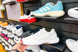 white adidas shoe held by shoe display