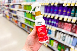 person holding a bottle of hair detangler in front of a shelf