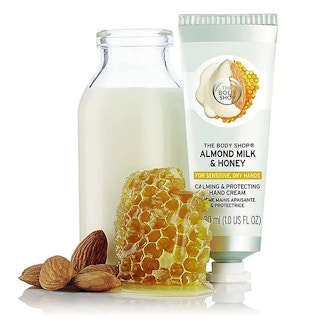 Hand cream tube, a honeycomb, and a bottle of milk on a white background