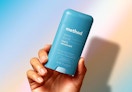 a hand holding a blue stick of deodorant 