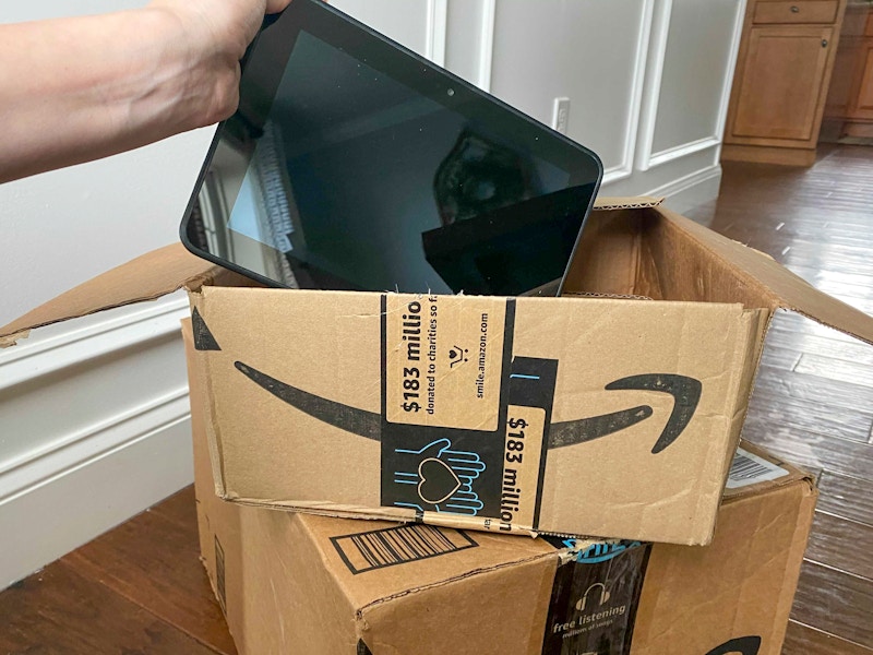 An amazon fire tablet held over an amazon box