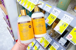 person holding 2 bottles of shea moisture shampoo and conditioner