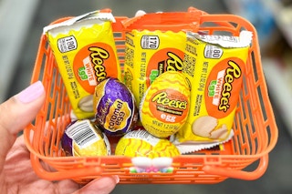 hand holding small basket with Cadbury mini eggs and Reese's chocolate egg candy inside