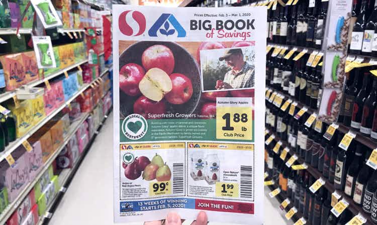 Person holding a Safeway Albertsons weekly ad in store
