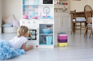 stock photo of girl playing with plum play wooden kitchen playset
