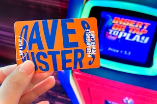 a person going to tap their Dave and Busters power card on an arcade machine