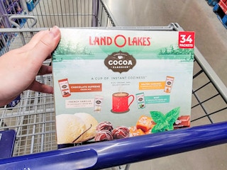 hand holding a box of land o lakes hot cocoa packets in a cart