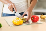 woman cutting peppers on glass cutting board 