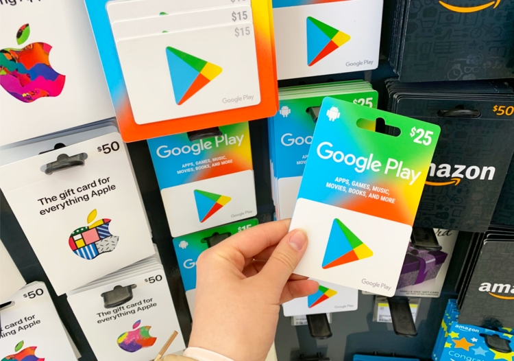 Hand holding Google Play gift card in front of gift card display