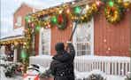 man using pole to hang up Christmas lights