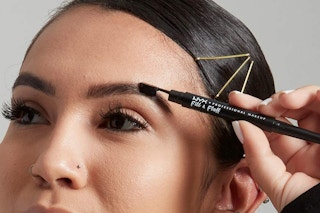 a woman using a nyx eyebrow pencil