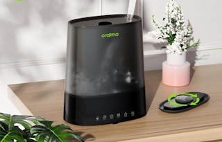 a black humidifier sitting on a wooden table next to flowers