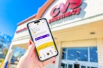 hand holding a smartphone displaying a kcl app 1-clip deal outside of a cvs store