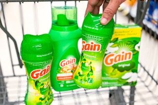 hand placing gain scent boosters in shopping cart with other gain laundry items